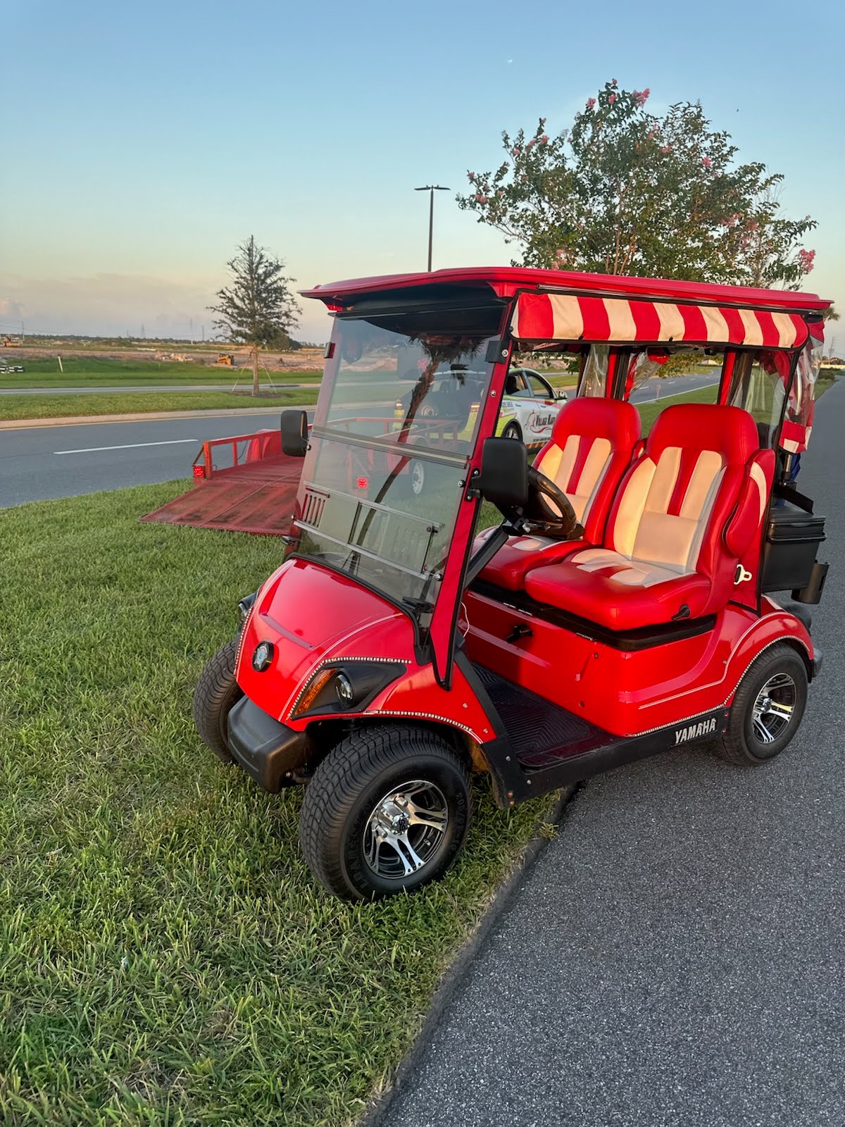 Red Yamaha golf cart beside a village road
