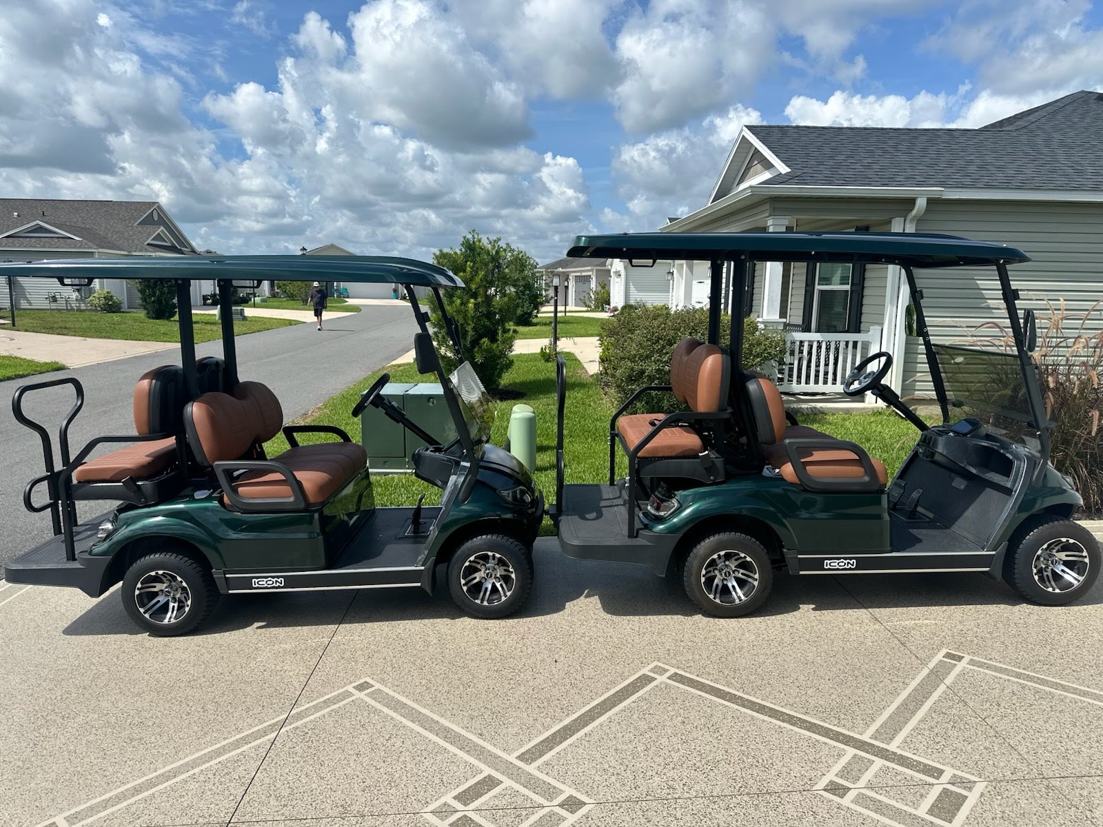Two green golf carts parked outside a village home